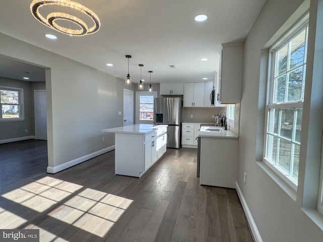 kitchen featuring white cabinetry, a center island, hanging light fixtures, stainless steel fridge, and a chandelier