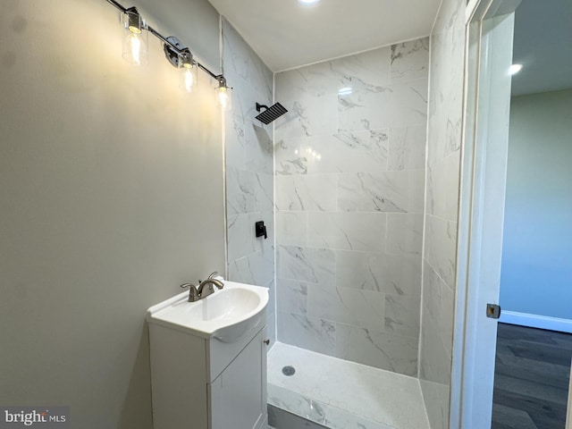 bathroom featuring hardwood / wood-style flooring, vanity, and tiled shower