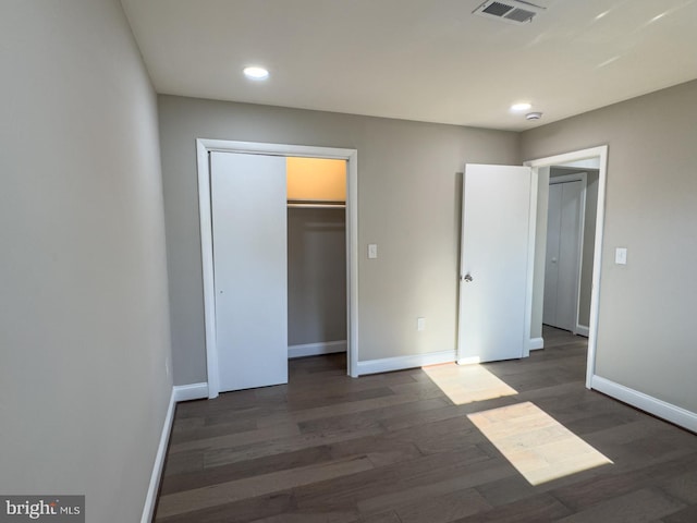 unfurnished bedroom featuring a spacious closet, a closet, and dark wood-type flooring