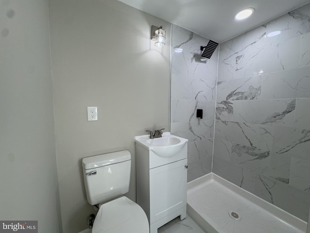 bathroom with tiled shower, vanity, and toilet