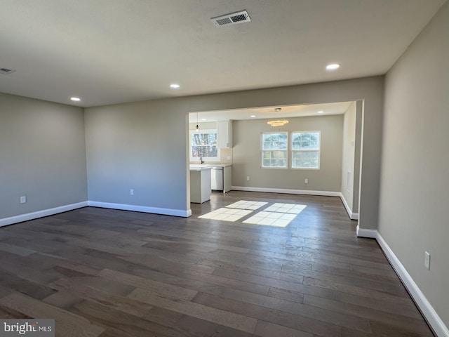 unfurnished living room featuring dark hardwood / wood-style floors and an inviting chandelier