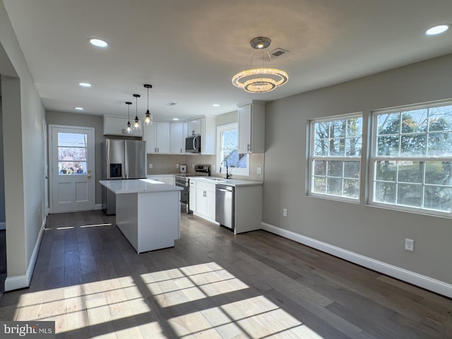 kitchen with white cabinetry, plenty of natural light, a kitchen island, and stainless steel appliances