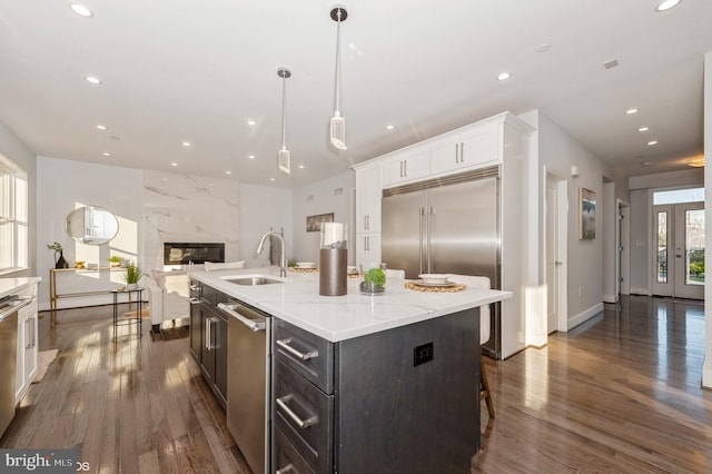 kitchen featuring dark hardwood / wood-style flooring, sink, white cabinets, hanging light fixtures, and an island with sink