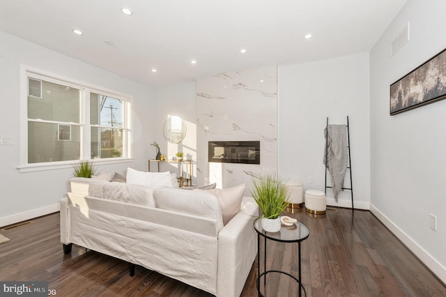 living room featuring a premium fireplace and dark wood-type flooring