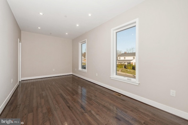 unfurnished room featuring a healthy amount of sunlight and dark wood-type flooring