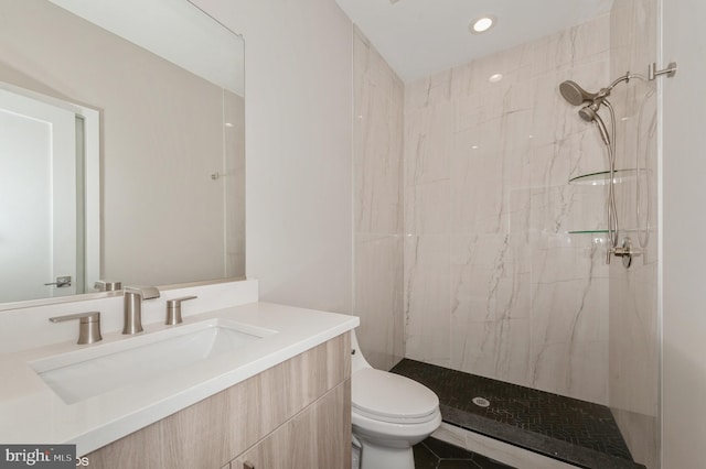 bathroom with tile patterned flooring, a tile shower, vanity, and toilet