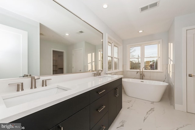 2418 Taney Rd, Baltimore, MD 21209 - bathroom featuring recessed lighting, double vanity, a freestanding tub, and marble finish floors