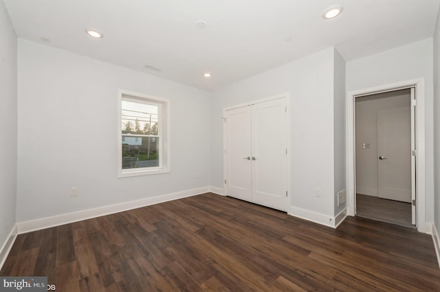 unfurnished bedroom featuring a closet and dark hardwood / wood-style floors