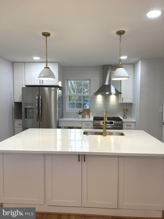 kitchen featuring decorative backsplash, wall chimney exhaust hood, stainless steel appliances, sink, and white cabinetry