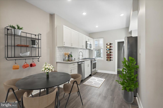 kitchen with white cabinetry, dark wood-type flooring, appliances with stainless steel finishes, and tasteful backsplash