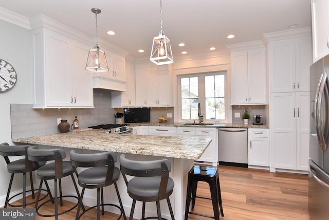 kitchen featuring light stone countertops, white cabinets, decorative light fixtures, and appliances with stainless steel finishes