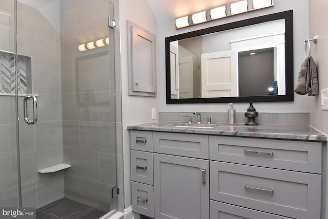 bathroom with a shower with door, vanity, and lofted ceiling