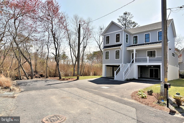 20682 Maple St, Rehoboth Beach, DE 19971 - view of front of house featuring a standing seam roof, asphalt driveway, stairway, a metal roof, and covered porch