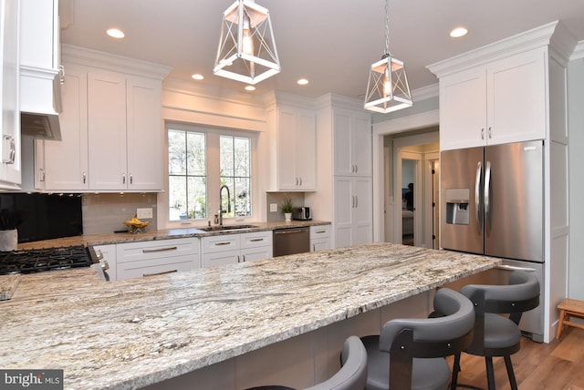 kitchen with a breakfast bar, sink, white cabinets, and appliances with stainless steel finishes