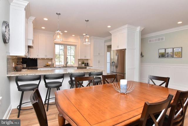 dining area with light hardwood / wood-style floors, ornamental molding, sink, and french doors