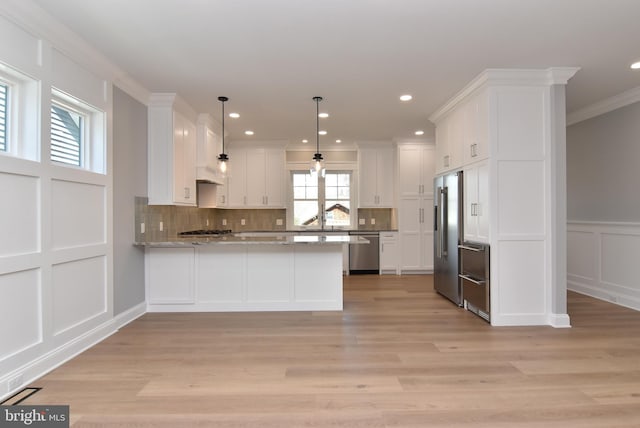 20682 Maple St, Rehoboth Beach, DE 19971 - kitchen featuring stainless steel appliances, a peninsula, a decorative wall, ornamental molding, and white cabinets