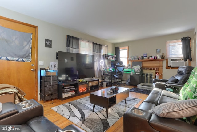 living room featuring a fireplace, light hardwood / wood-style flooring, and cooling unit