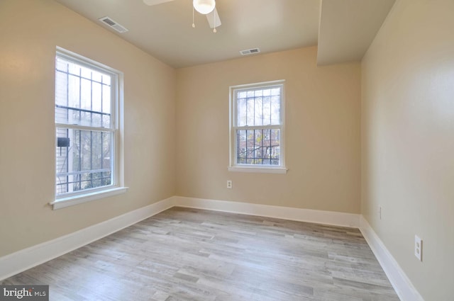 spare room featuring a wealth of natural light, light hardwood / wood-style flooring, and ceiling fan