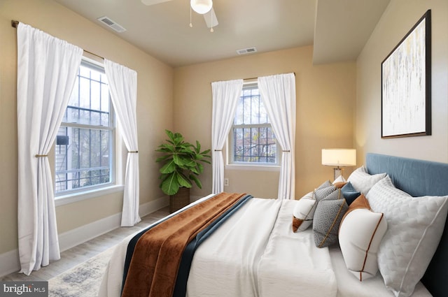 bedroom featuring ceiling fan, light wood-type flooring, and multiple windows