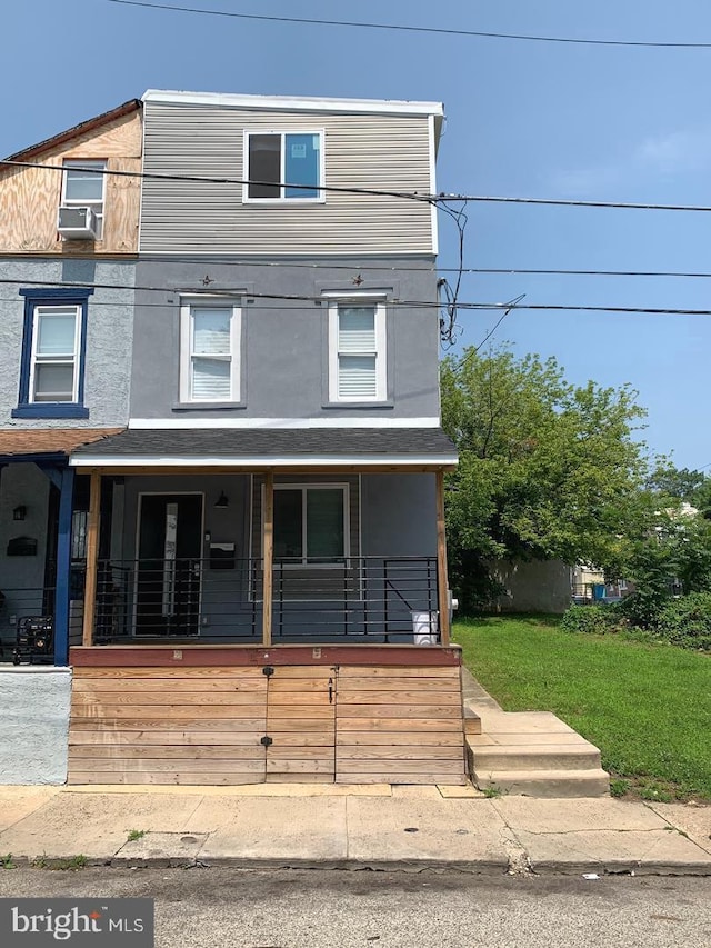 view of front facade with cooling unit, covered porch, and a front yard