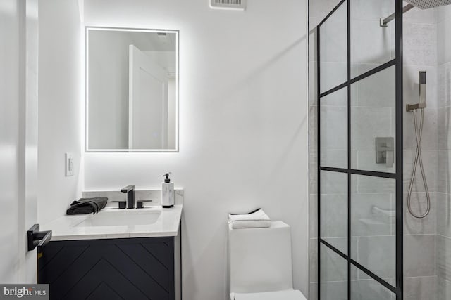 bathroom with a tile shower, vanity, and toilet