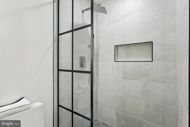 bathroom featuring a tile shower and toilet