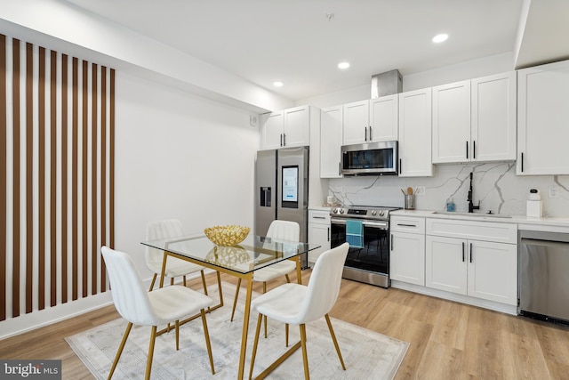 kitchen with white cabinets, light hardwood / wood-style floors, sink, and stainless steel appliances