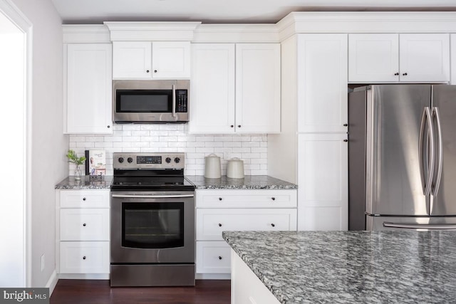 kitchen with white cabinetry, stainless steel appliances, tasteful backsplash, and dark stone counters