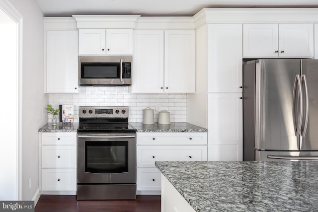 kitchen featuring tasteful backsplash, appliances with stainless steel finishes, dark stone countertops, and white cabinets