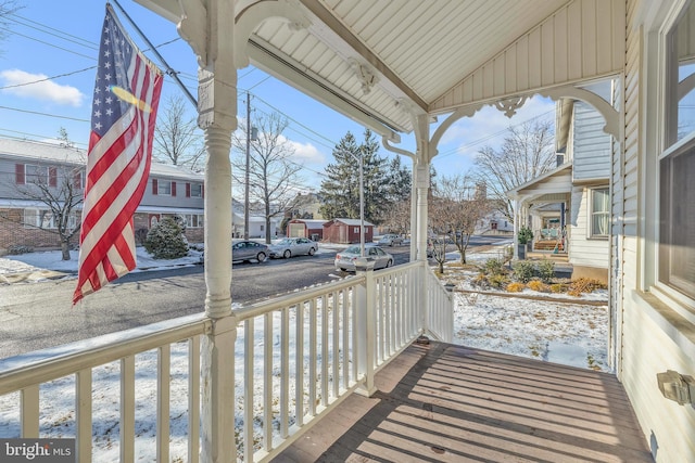 snow covered back of property featuring a porch