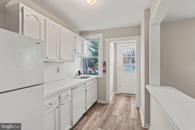 kitchen with white cabinetry, white appliances, sink, and light hardwood / wood-style flooring