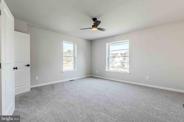 carpeted spare room featuring plenty of natural light and ceiling fan