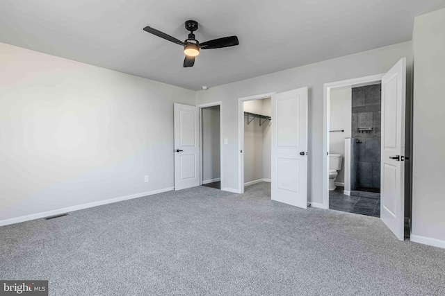 unfurnished bedroom featuring carpet, a walk in closet, ceiling fan, connected bathroom, and a closet