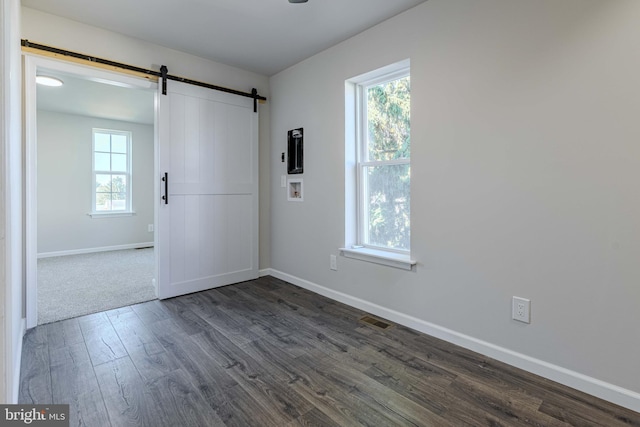 spare room with dark hardwood / wood-style floors and a barn door