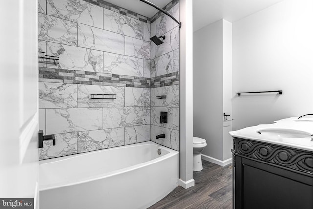 full bathroom featuring hardwood / wood-style flooring, tiled shower / bath combo, toilet, and vanity