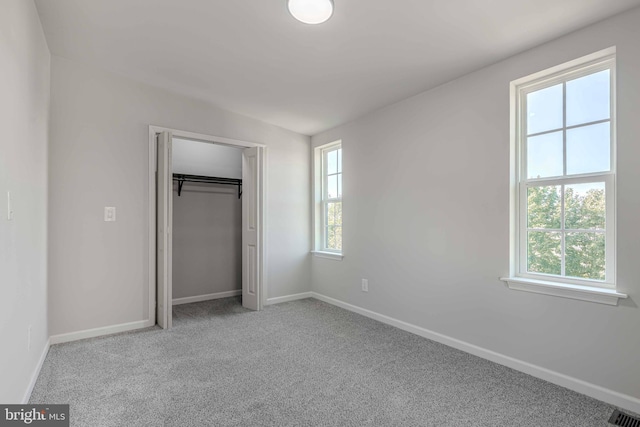 unfurnished bedroom featuring a closet, light carpet, and multiple windows