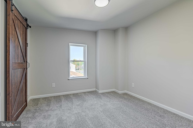 unfurnished room featuring a barn door and carpet floors