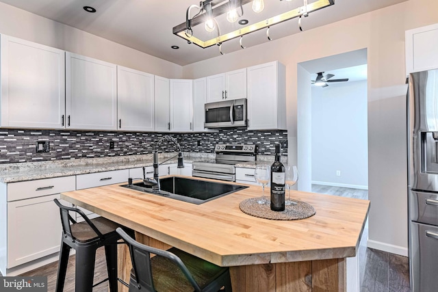 kitchen featuring white cabinets, appliances with stainless steel finishes, and decorative backsplash