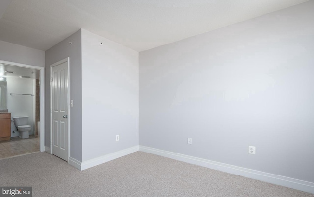 interior space with ensuite bathroom and light carpet