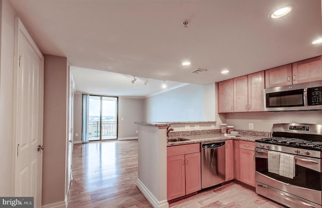 kitchen featuring light wood-type flooring, light stone countertops, ornamental molding, kitchen peninsula, and stainless steel appliances