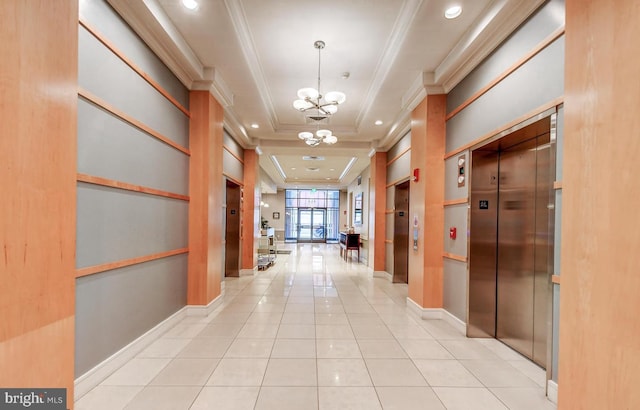 hall with light tile patterned floors, a tray ceiling, elevator, and a notable chandelier