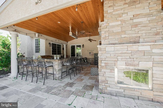 view of patio featuring ceiling fan and a bar