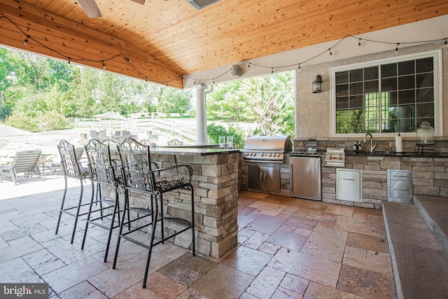 view of patio featuring an outdoor kitchen, area for grilling, a wet bar, and ceiling fan