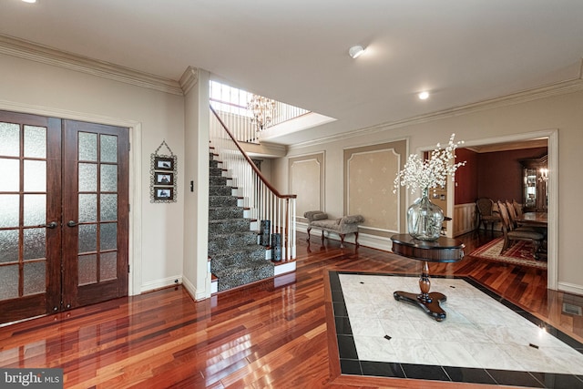 foyer with ornamental molding, french doors, wood-type flooring, and an inviting chandelier