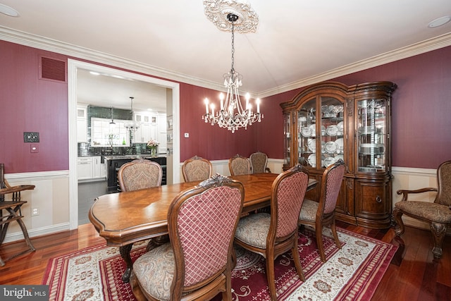 dining area featuring crown molding, a chandelier, and dark hardwood / wood-style flooring