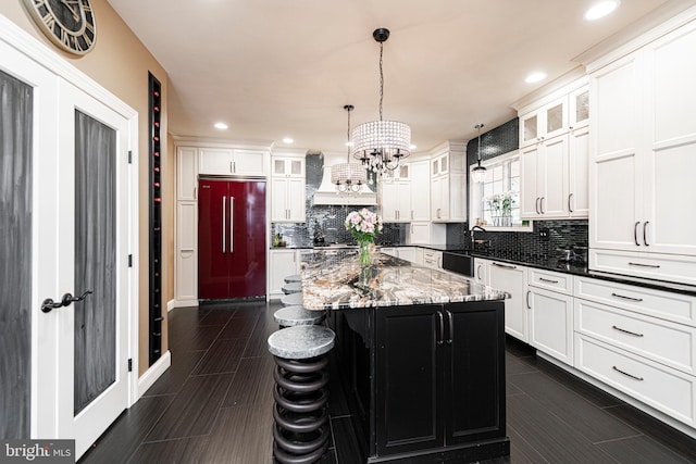 kitchen with a kitchen bar, a kitchen island, dark stone counters, paneled built in fridge, and decorative backsplash