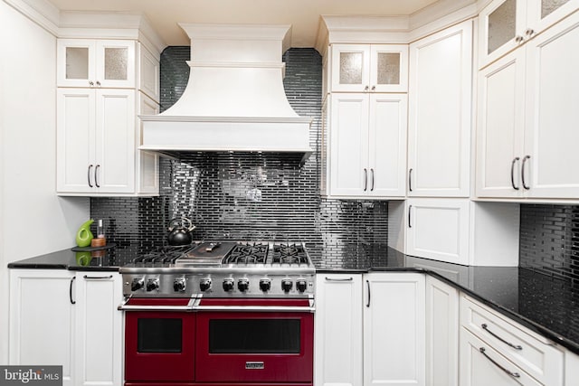 kitchen with white cabinetry, backsplash, double oven range, and custom range hood