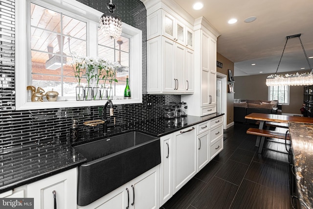 kitchen with white cabinets, pendant lighting, sink, and dark stone counters