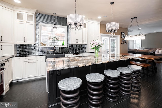 kitchen with pendant lighting, a chandelier, dark stone counters, and decorative backsplash