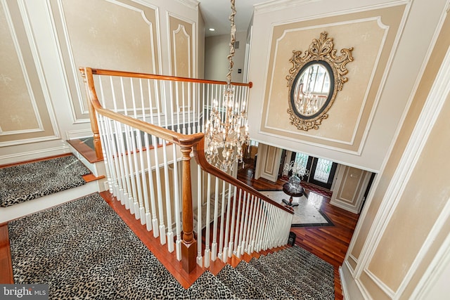 staircase with ornamental molding, a chandelier, and wood-type flooring